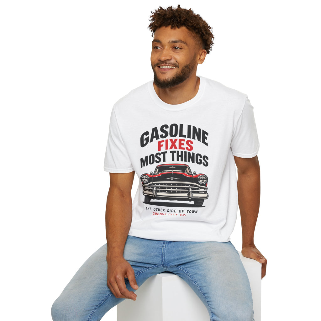 Seated man wearing the white “Gasoline Fixes Most Things” T-shirt with a red and black classic car print.