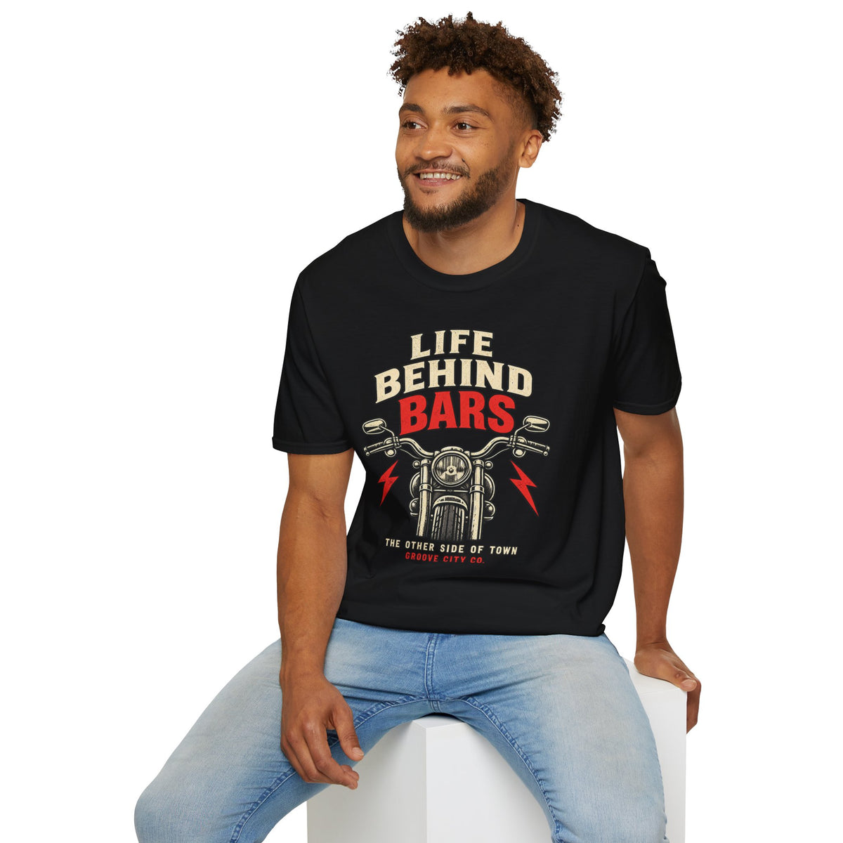 Seated man wearing a black “Life Behind Bars” motorcycle graphic T-shirt with red lightning bolts
