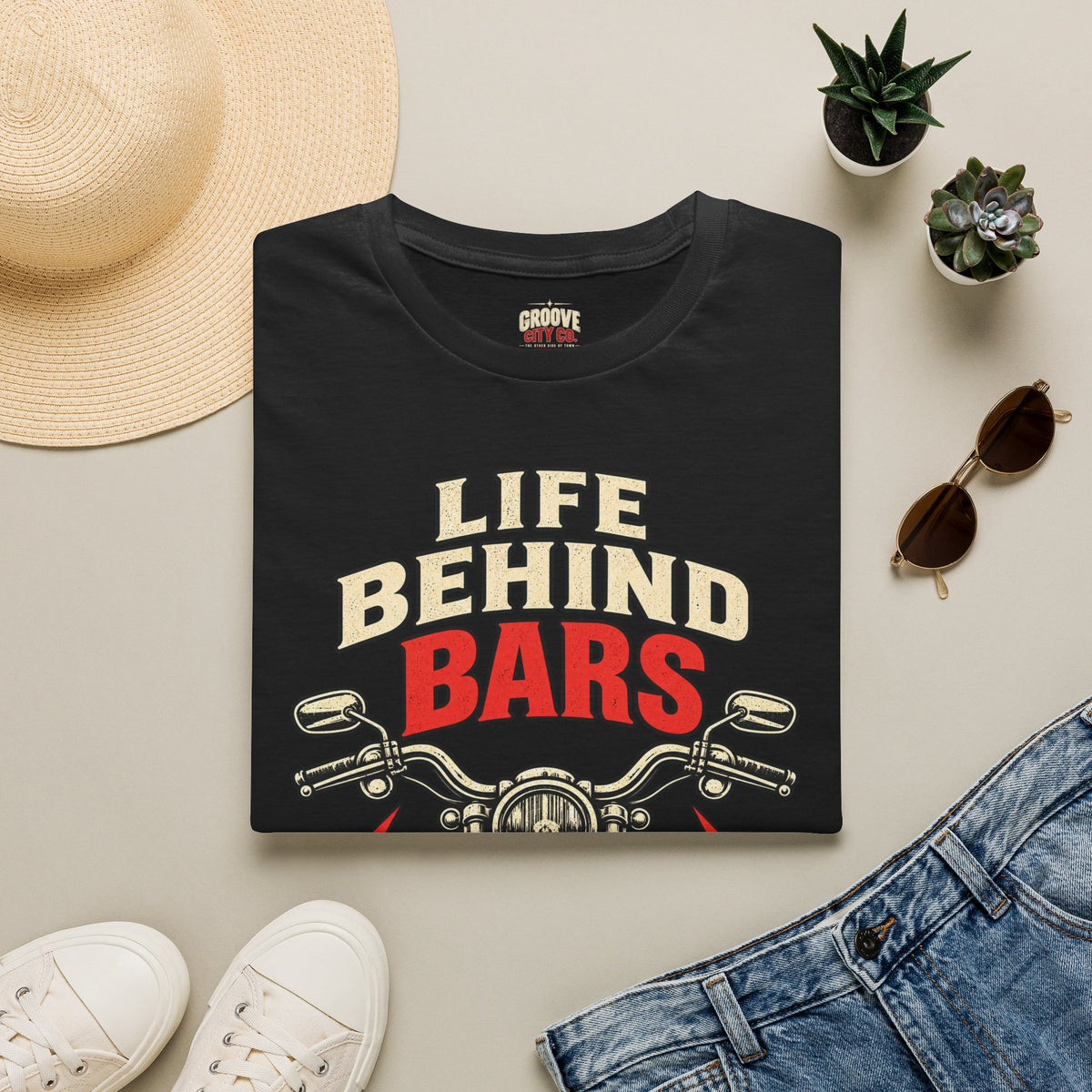 Folded black “Life Behind Bars” motorcycle T-shirt styled with jeans, sunglasses and a straw hat